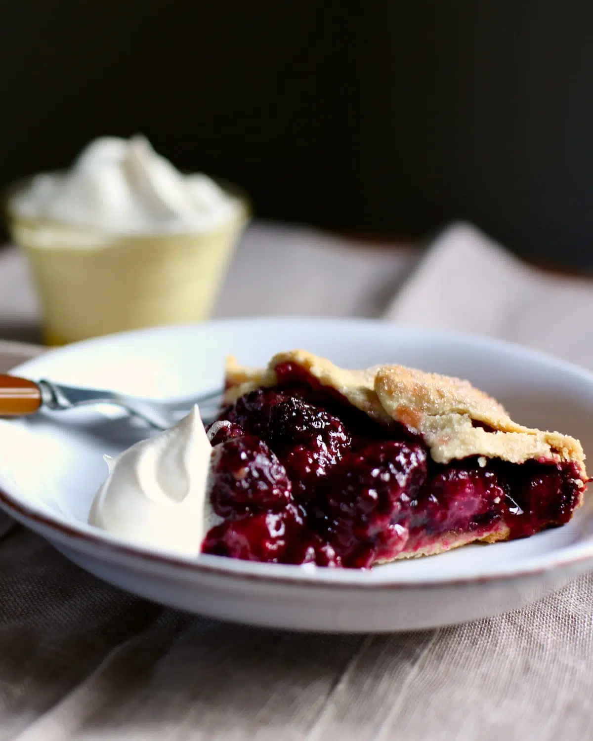 a piece of pie on a white plate and on a table.