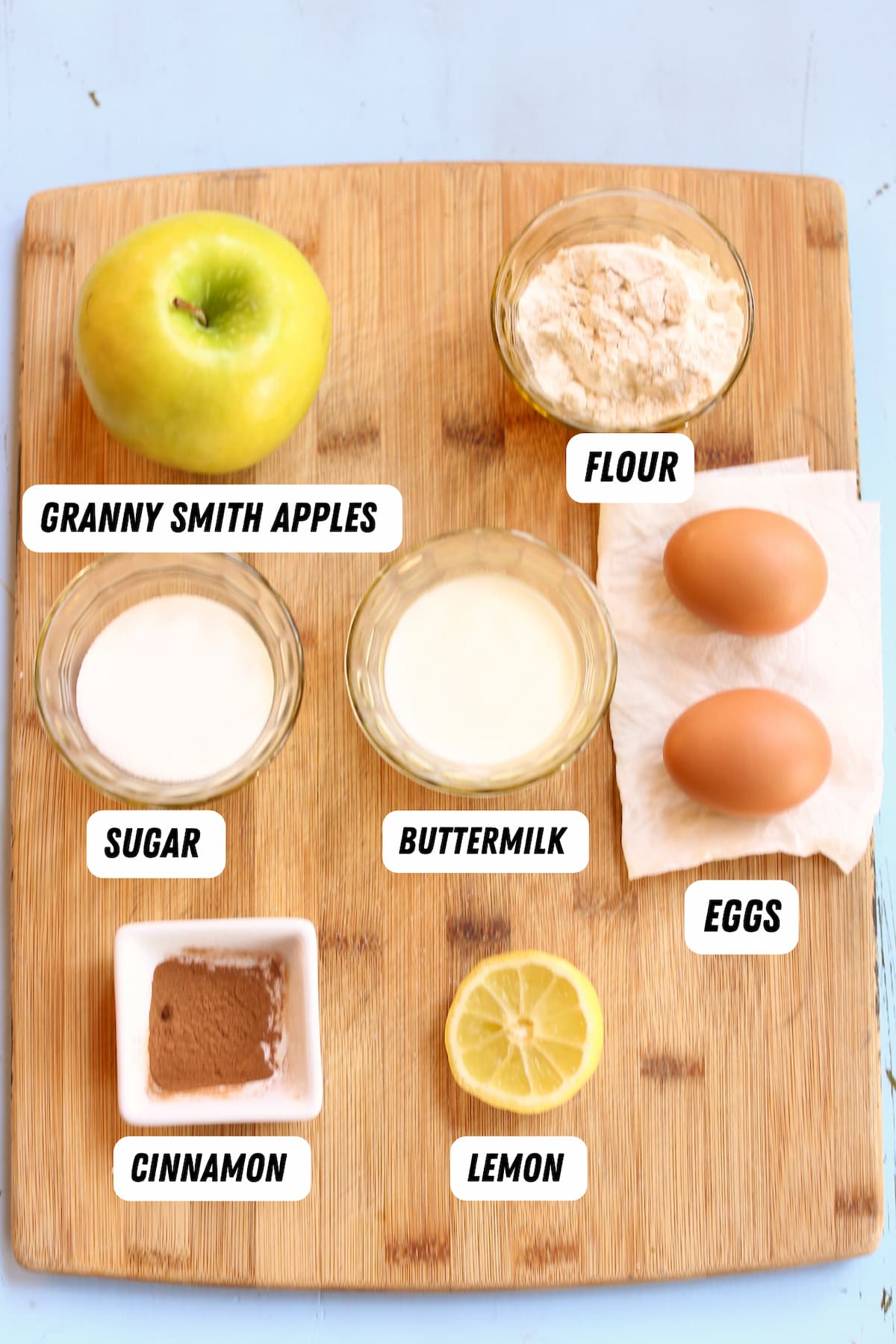 a cutting board with ingredients for apple fritters, captioned with the ingredient names.