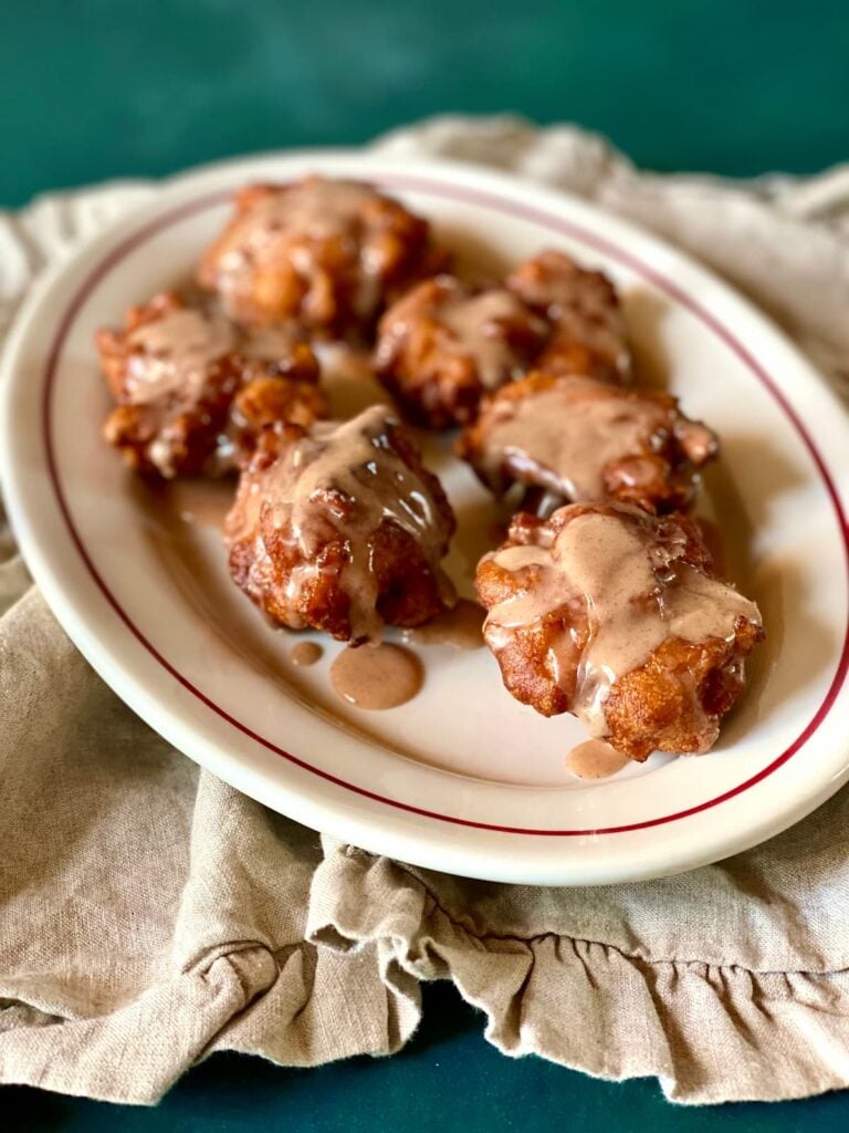 a side view of apple fritters on a table with a napkin.