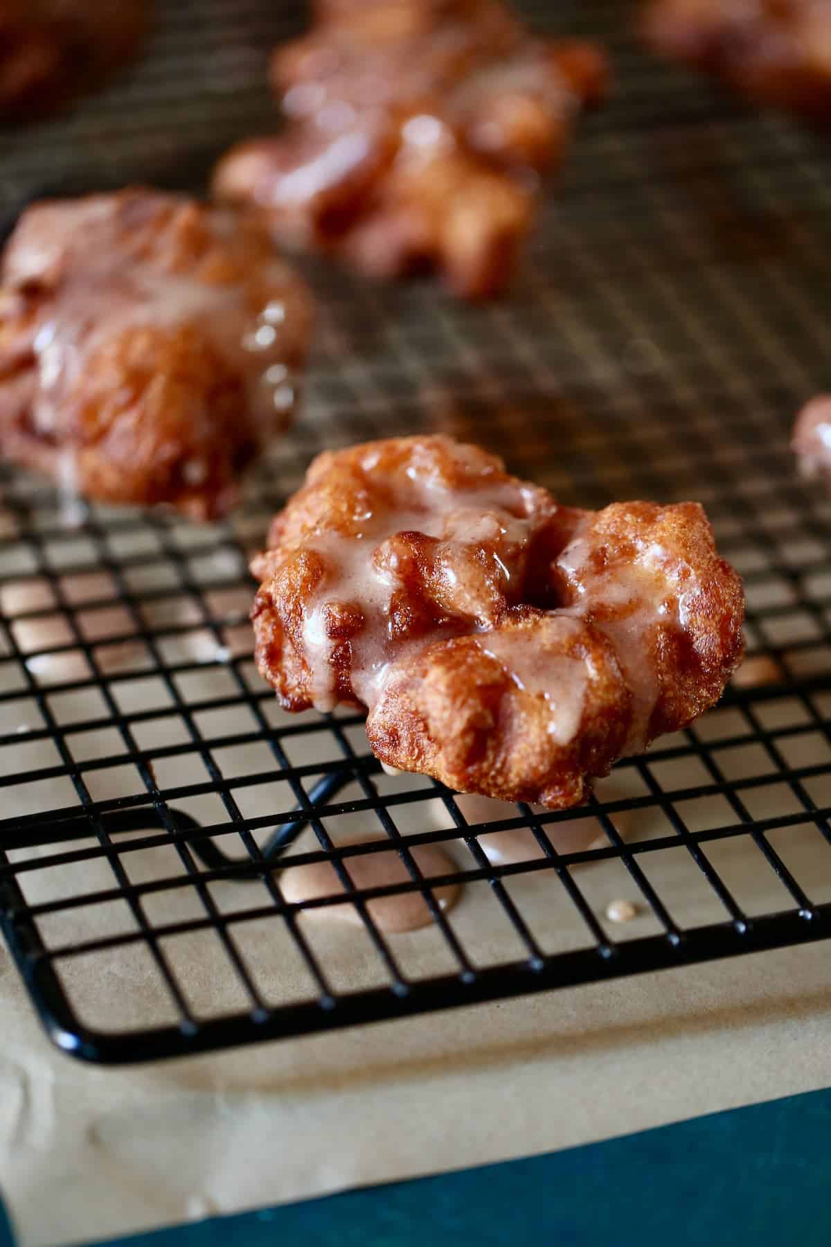 a close up photo of apple fritters on a wire cooling rack.