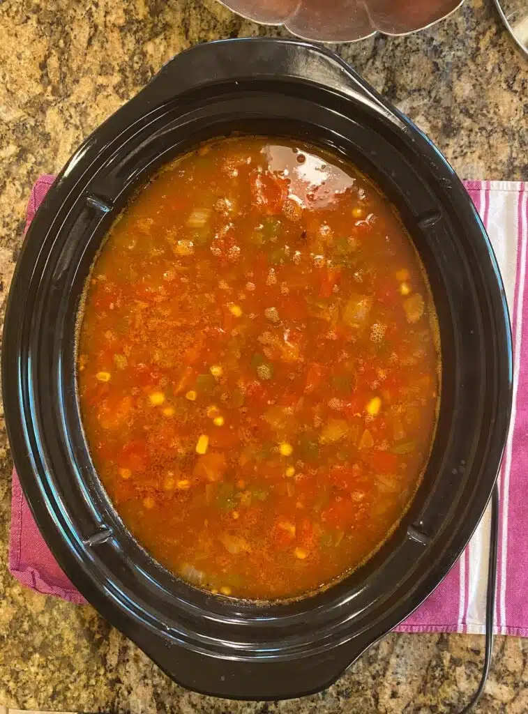an overhead photo of a slow cooker with red soup in it.