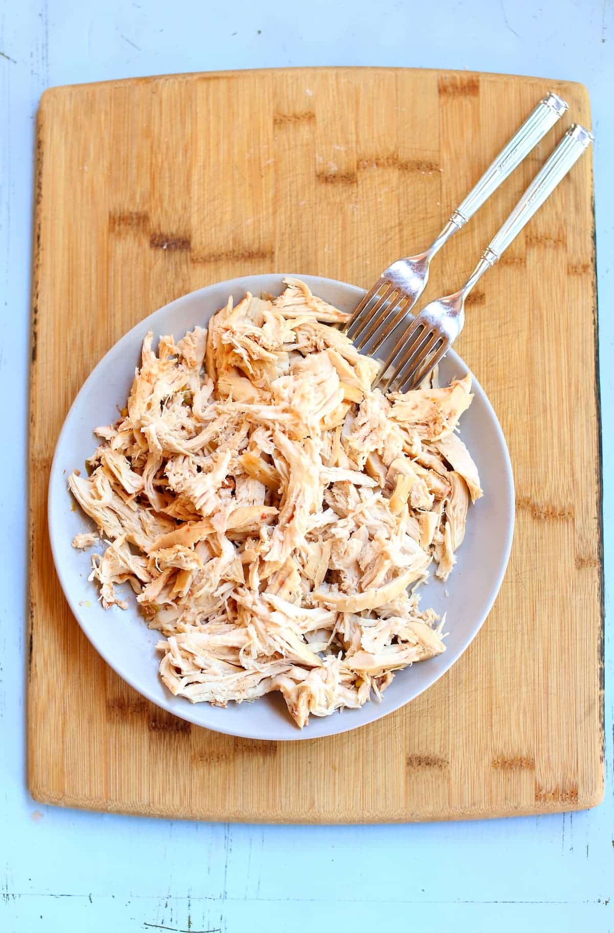 a photo of shredded chicken breasts and two forks on a plate.