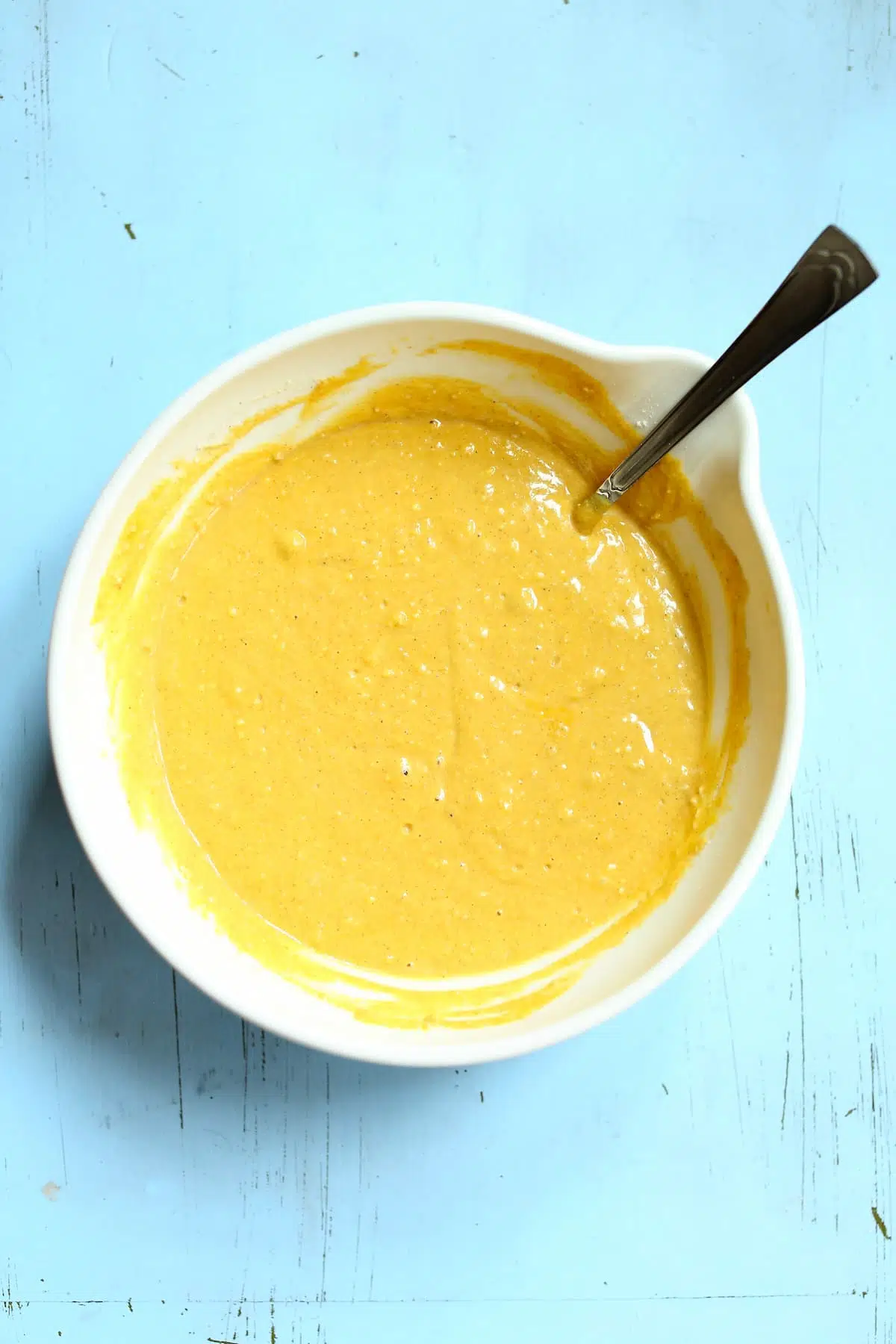 a white bowl with pumpkin waffle batter in it.