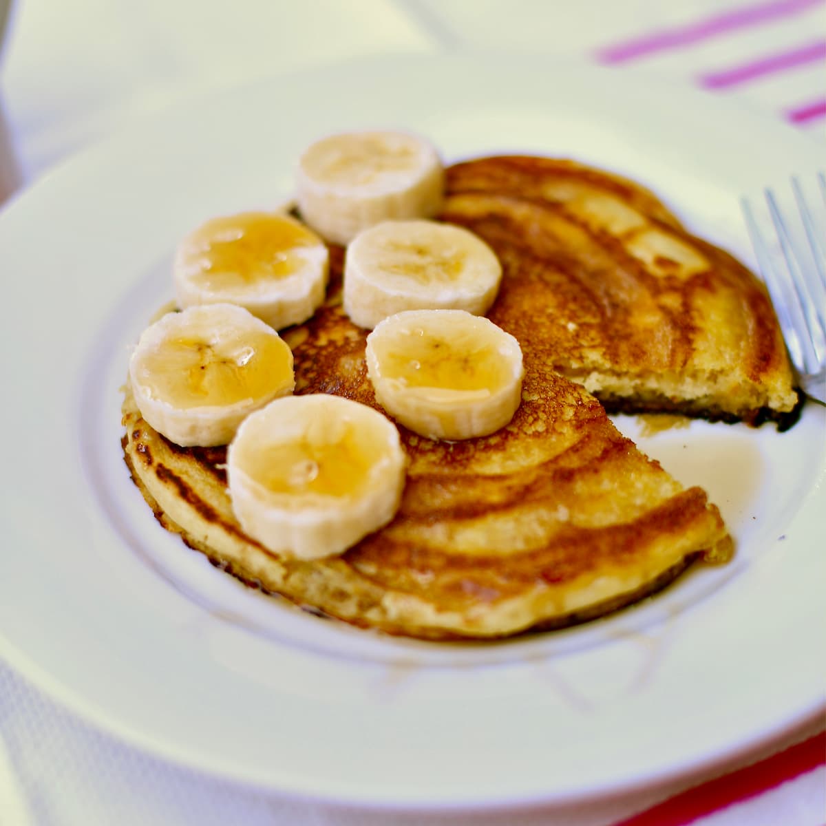 a white plate of pancakes with bananas.
