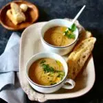 a tray with two soups and bread in it.