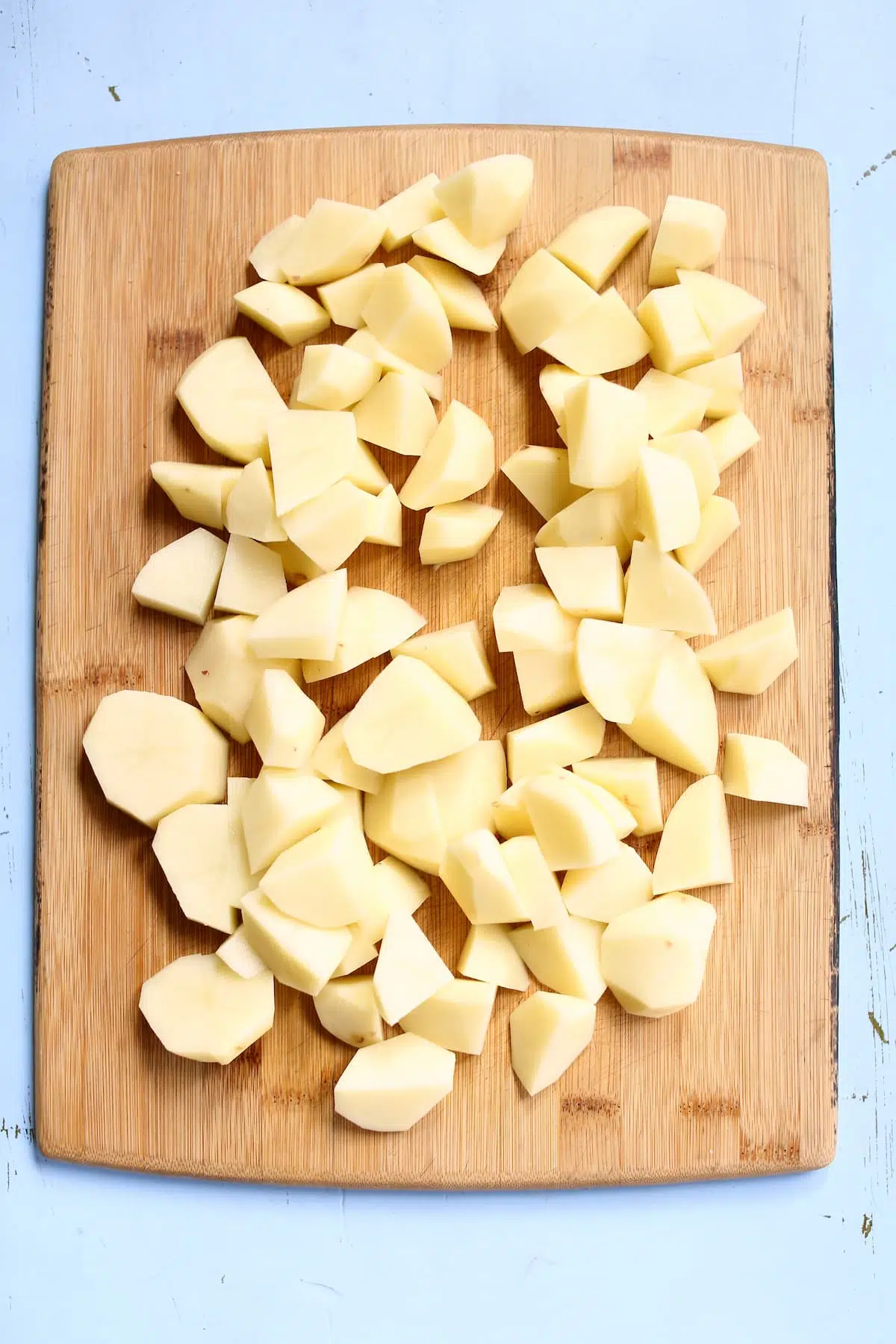 a cutting board with potatoes cut up.