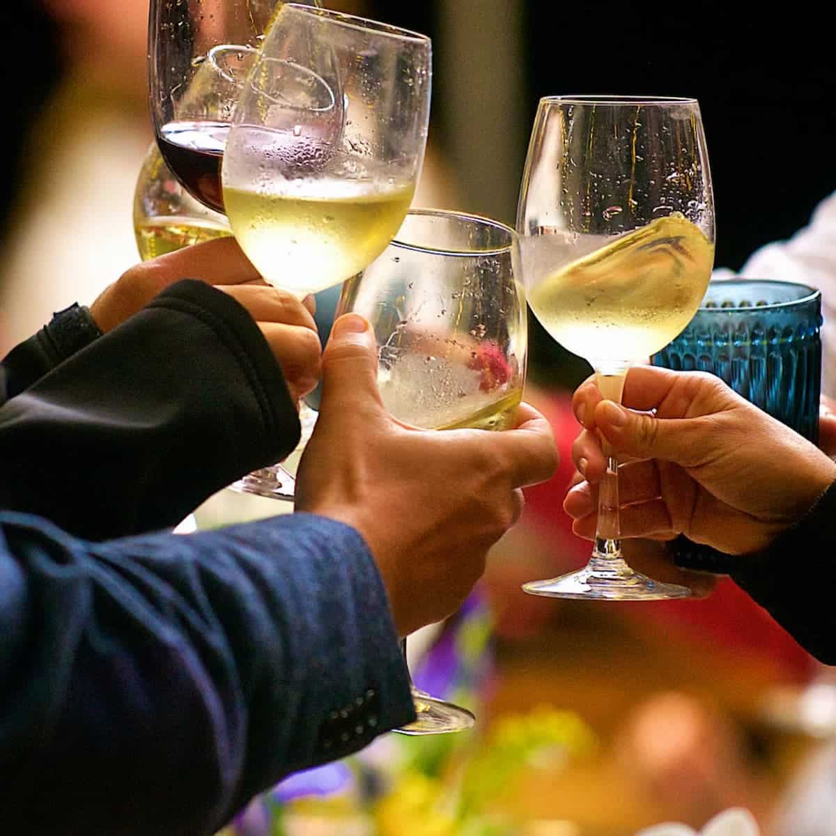 an image of several people holding wine glasses and clinking them together.