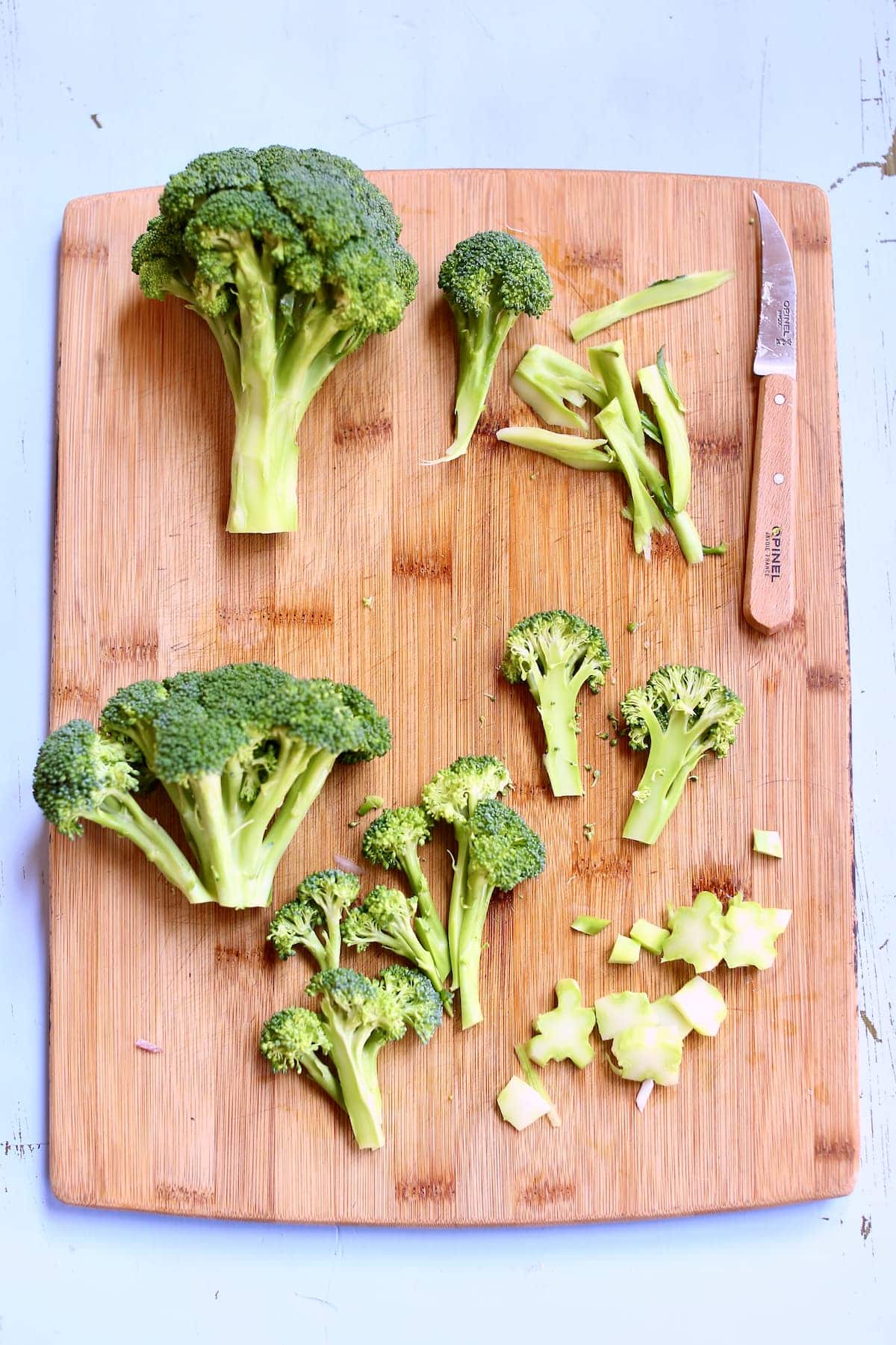 a cutting board of broccoli with a knife.
