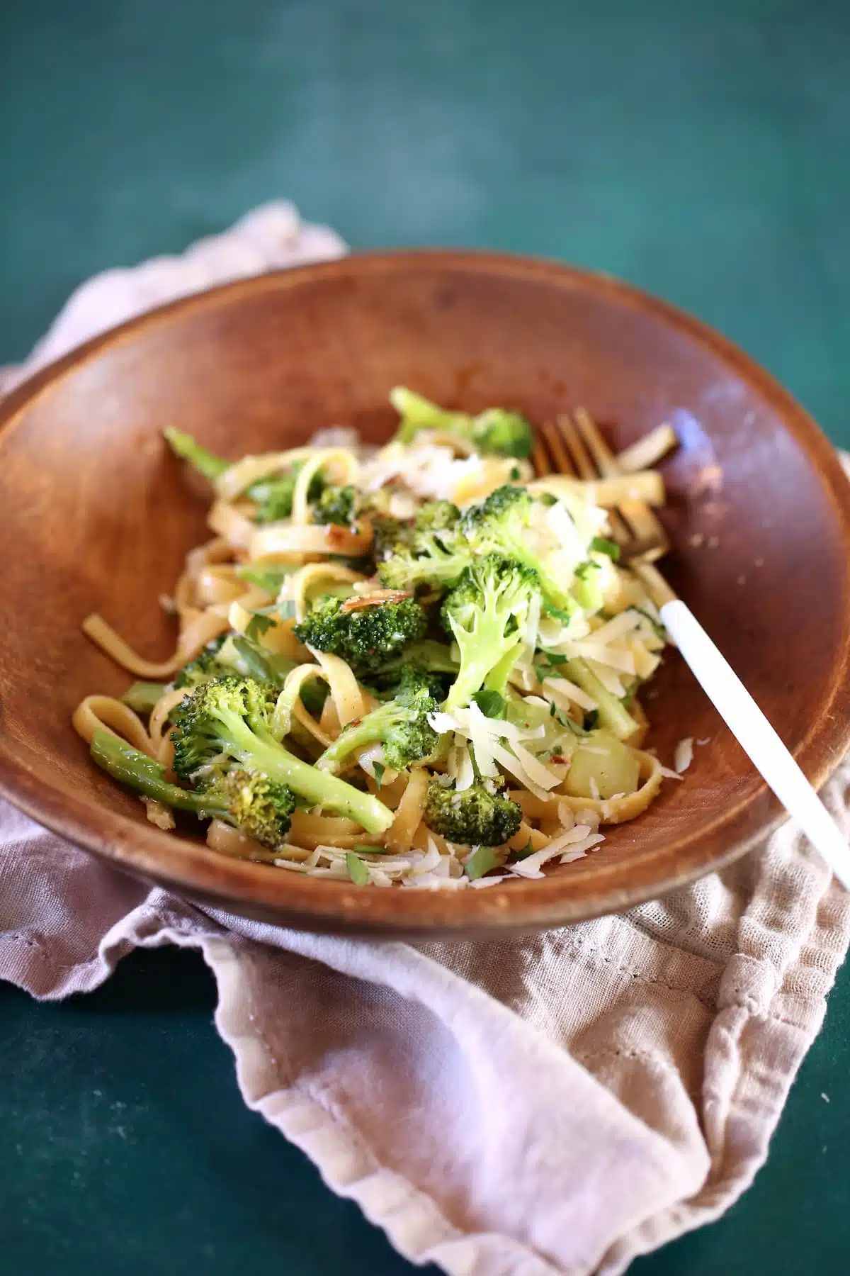 a close up photo of pasta and broccoli in a wooden bowl.