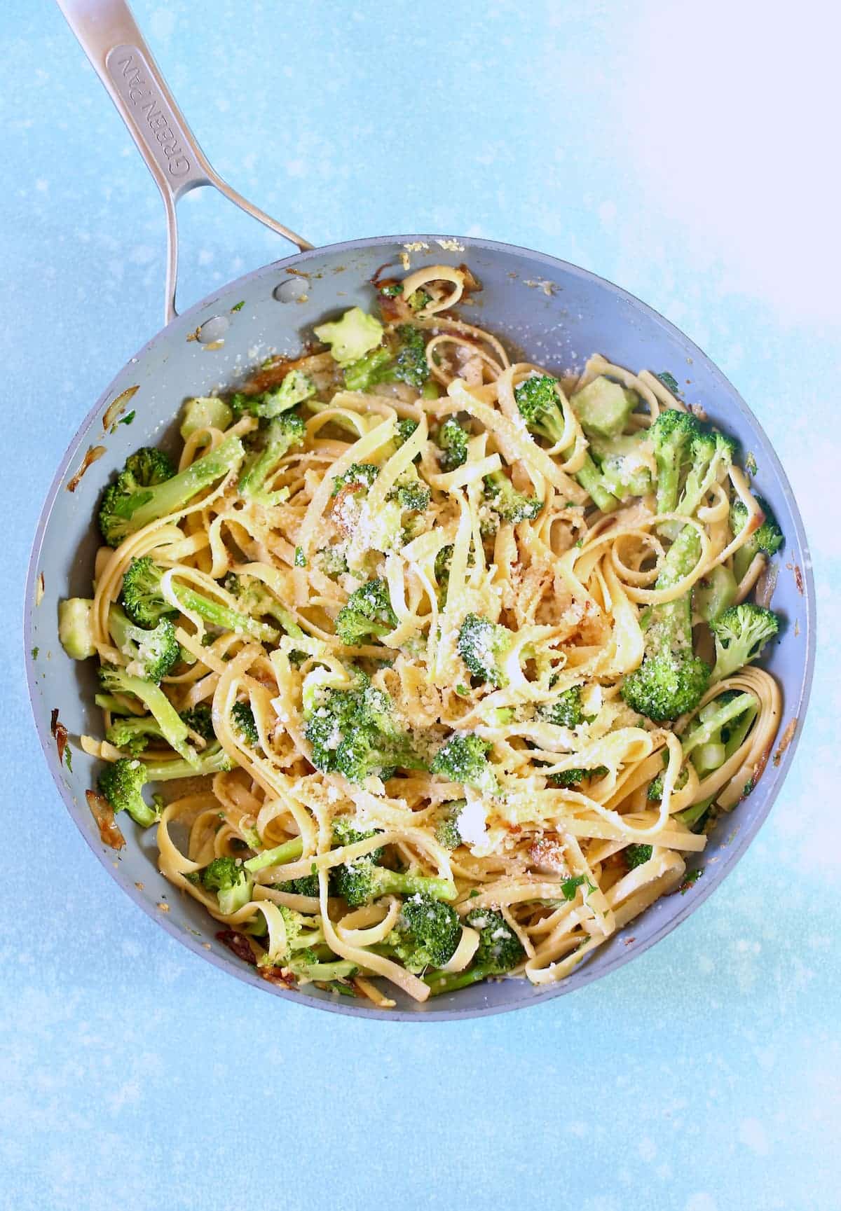 a skillet with pasta and broccoli in it.
