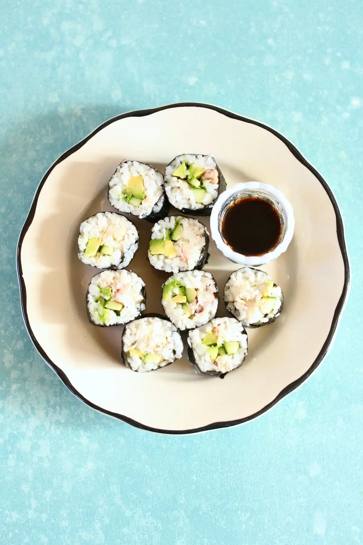 a small white plate with sushi rolls and sauce.