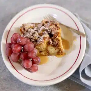 a small white plate with a brunch item and grapes on it.