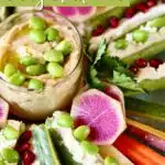 a close up photo of hummus dip on a veggie board.