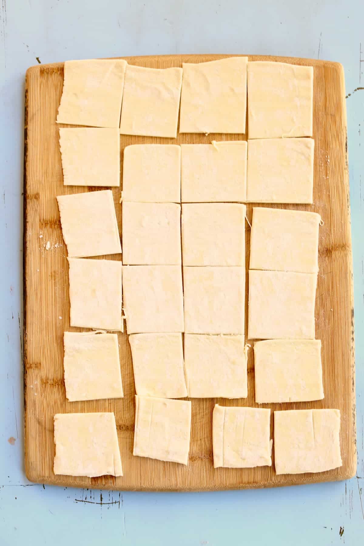 a cutting board of puff pastry cut into small squares.