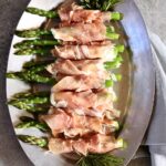 an overhead photo of asparagus appetizers on a silver platter.