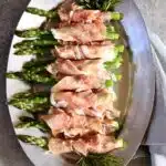 an overhead photo of asparagus appetizers on a silver platter.