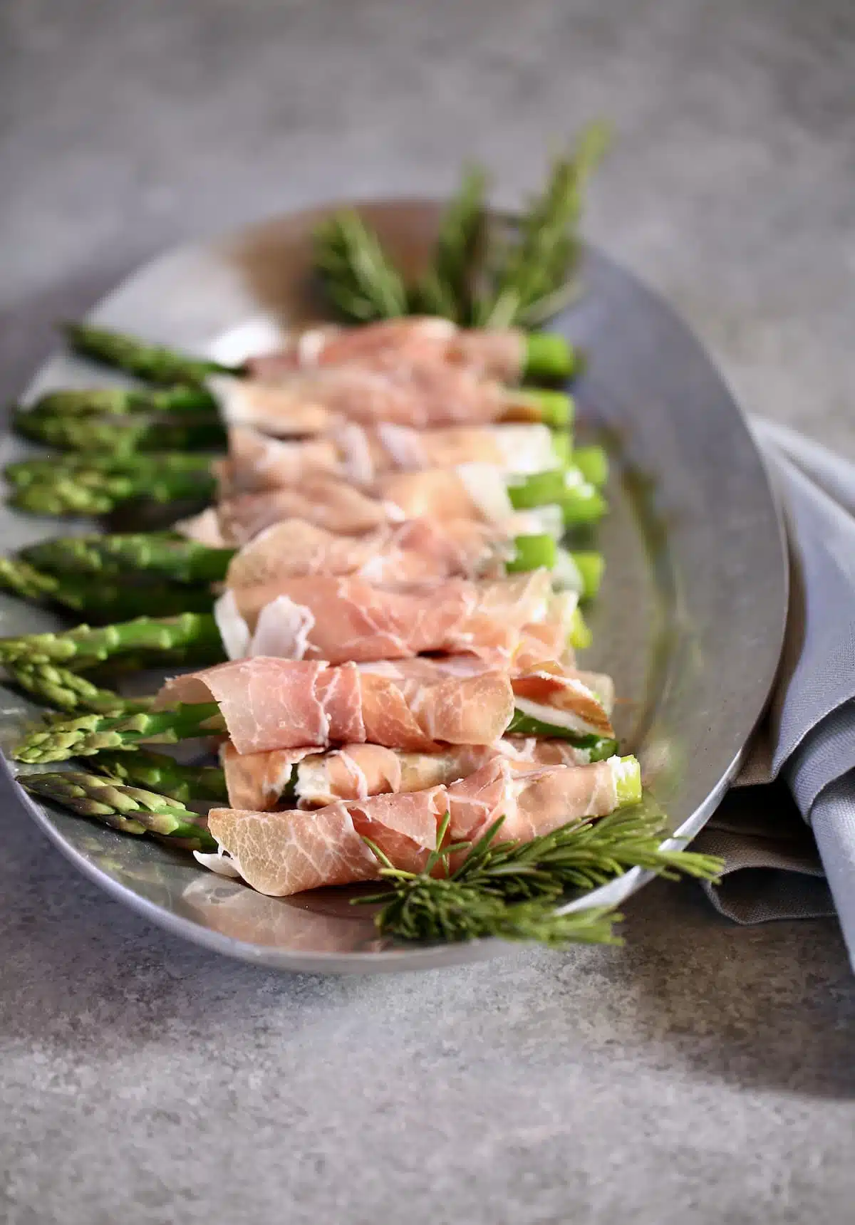 a side view of asparagus appetizers on a silver platter.
