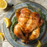 a pinterest image of a rotisserie chicken on a table with text overlay.