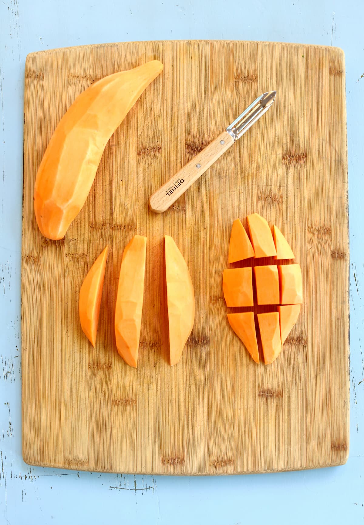 a cutting board with a sweet potato on it, in carious stages of cutting.