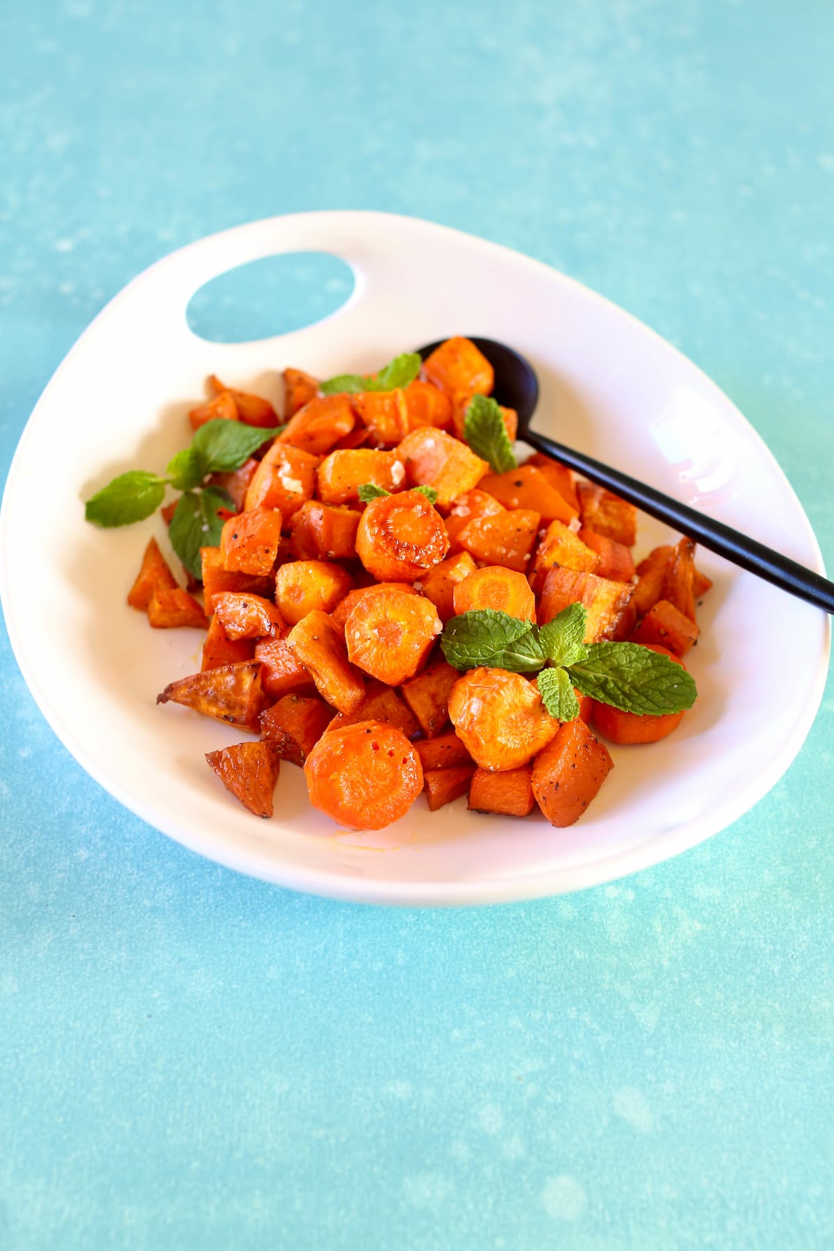 a bowl of carrots in a white bowl on a blue table.