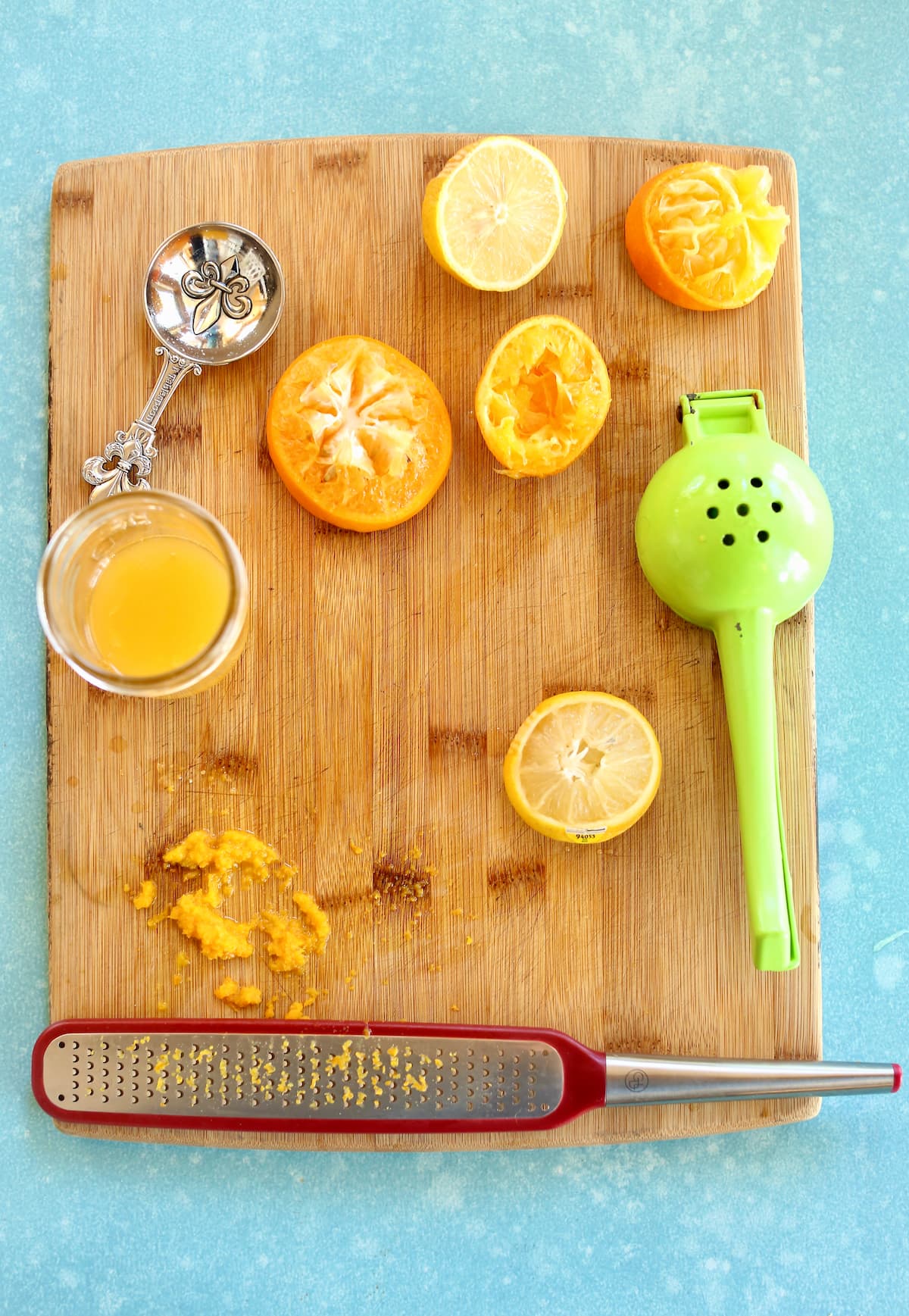 a cutting board with citrus fruits being squeezed for juice.