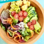 a salad in a wooden bowl on a blue table.