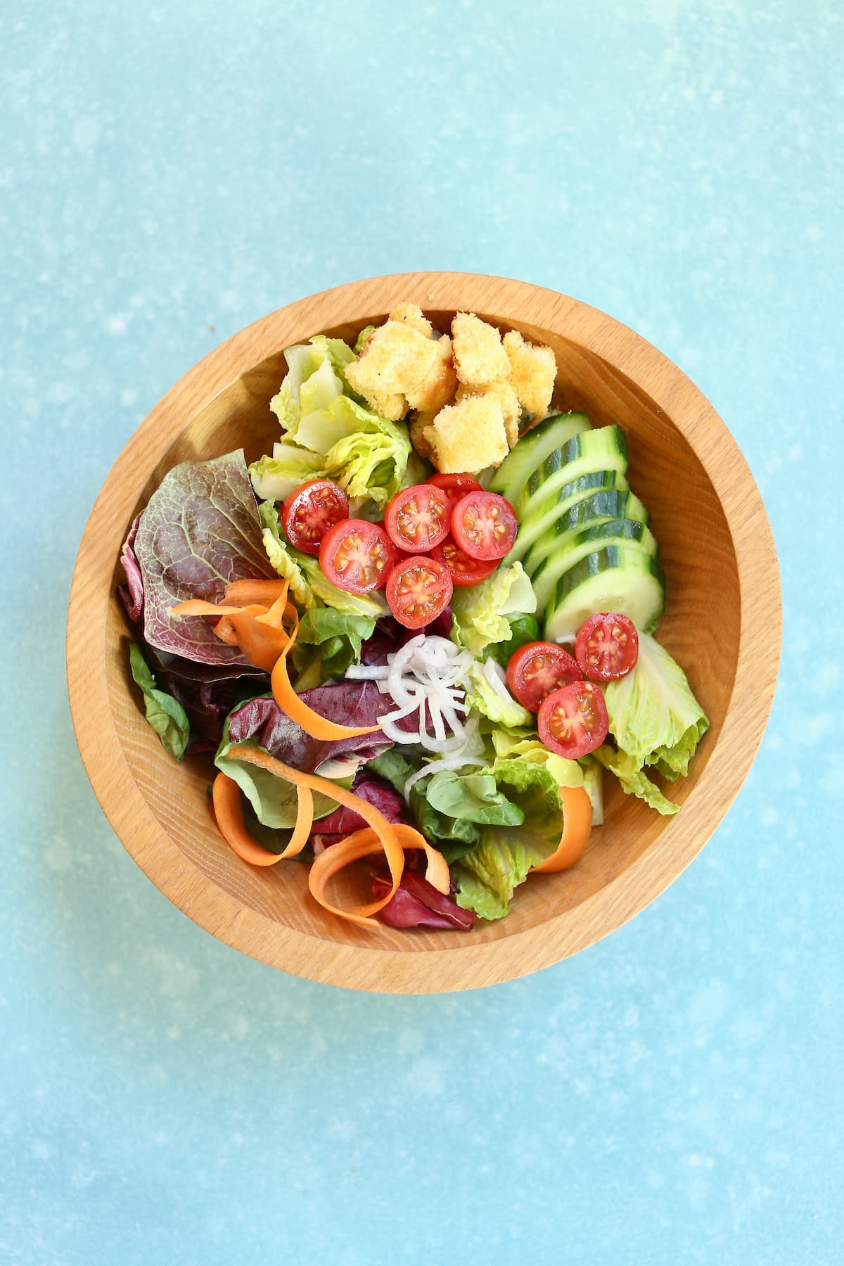 an overhead photo of a salad in a wooden bowl on a table. 