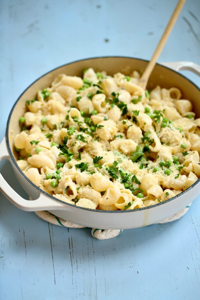 a skillet of pasta with a wooden spoon.