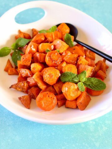 a side view of carrots and potatoes in a white bowl.