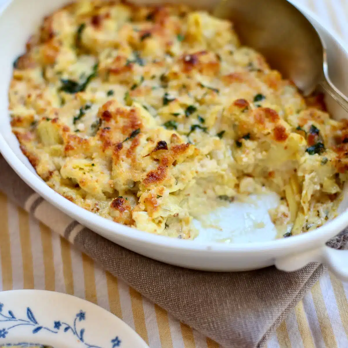 a white casserole dish of hot artichoke dip.