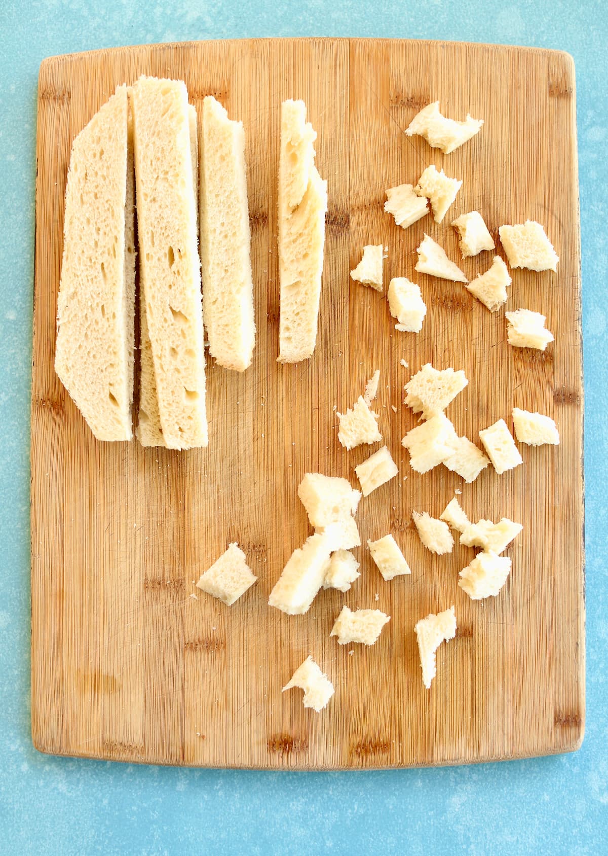 a cutting board of bread cut into chunks.