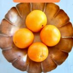 a silver bowl of oranges.