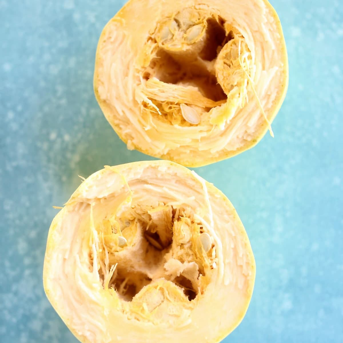 a square photo of a squash on a blue table.