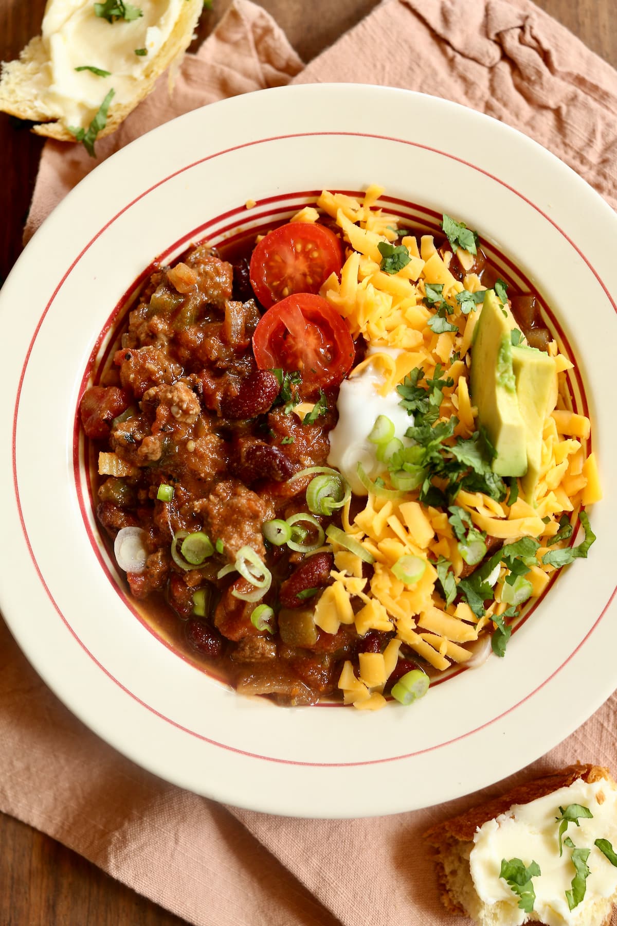 An overhead photo of a bowl of chili with fresh toppings.  