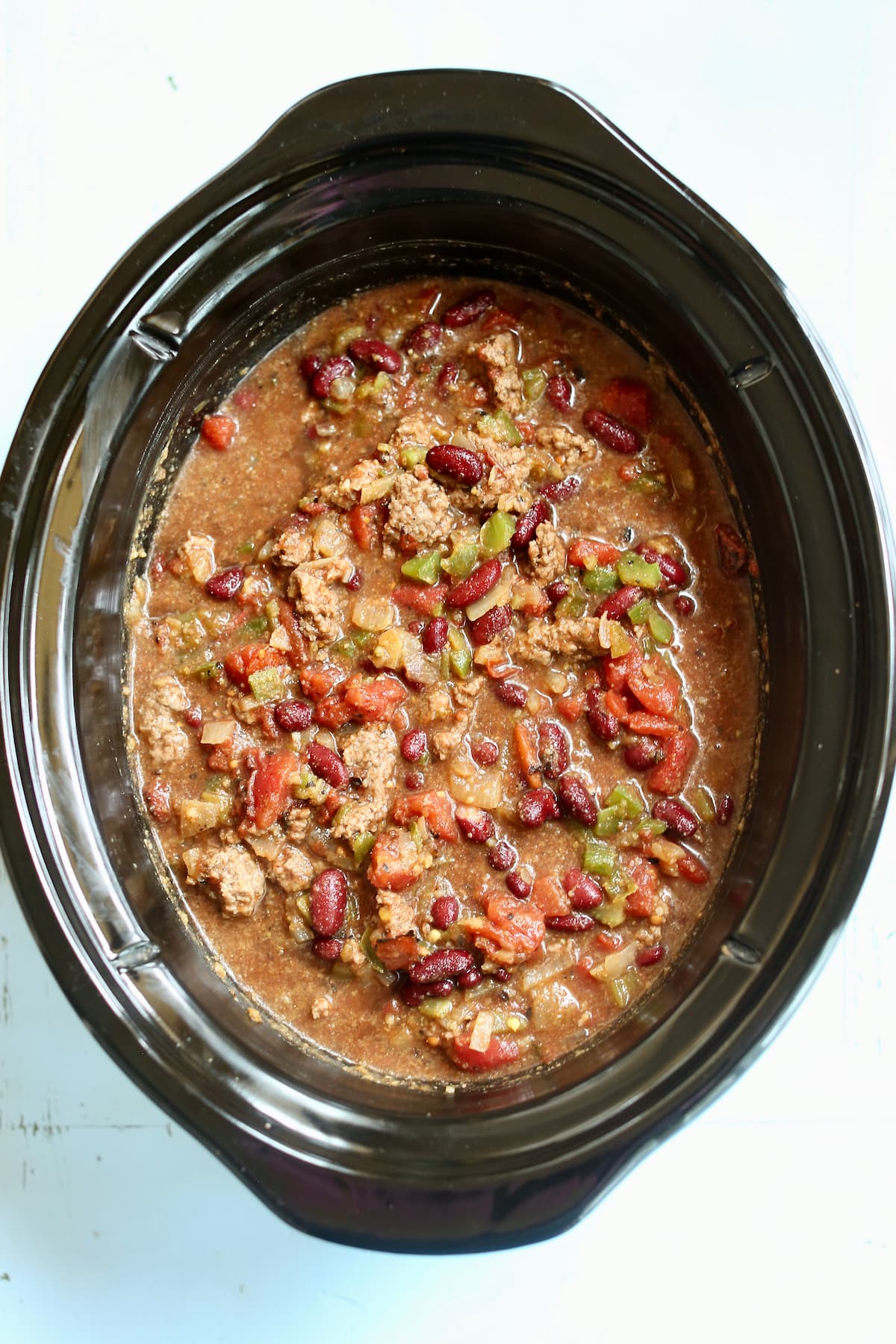 a crock pot vessel with the uncooked irish chili ingredents in it.
