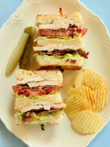 an overhead photo of a clubhouse sandwich with chips and pickles.