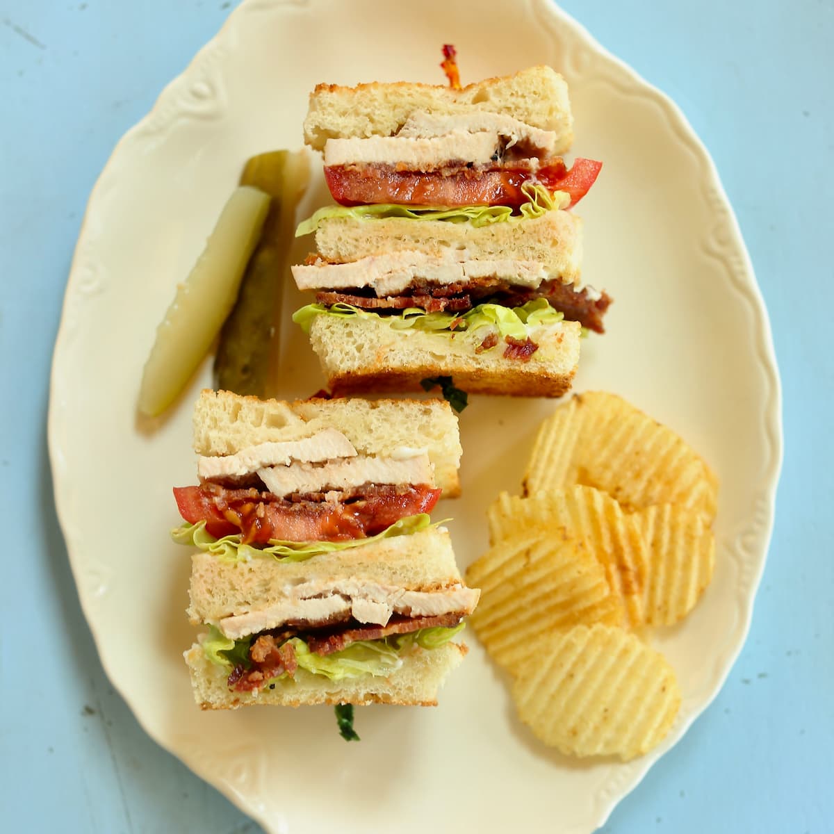 an overhead photo of a clubhouse sandwich with chips and pickles.