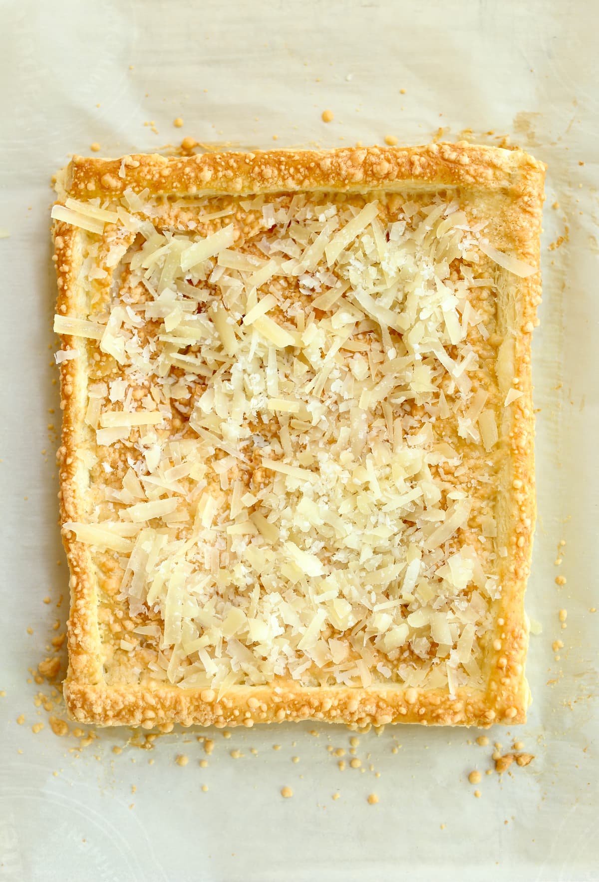 a photo of a baked puff pastry tart with cheese on it.