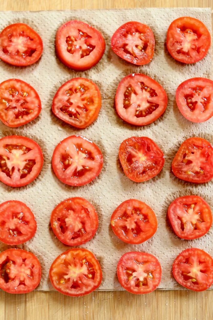 a close up photo of sliced tomatoes on natural paper towels.