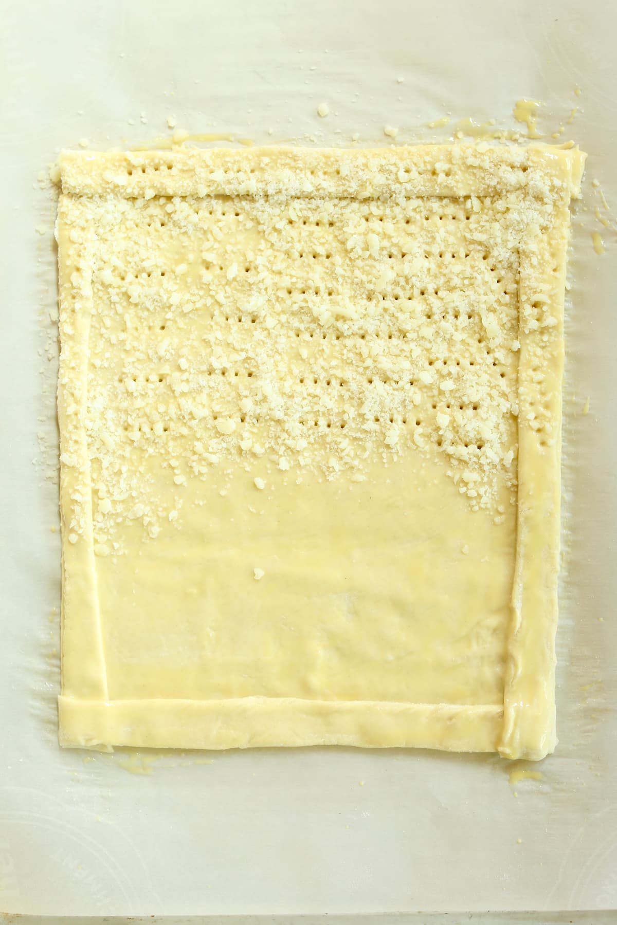 a photo of a raw puff pastry tart with cheese on one side.