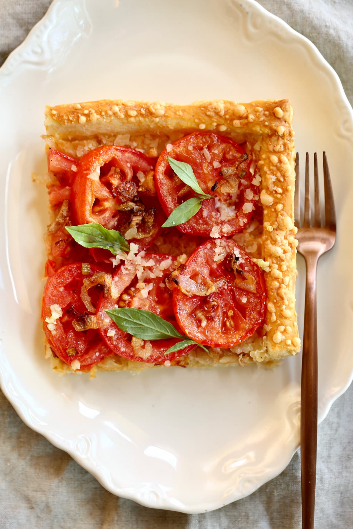 a square piece of tomato pie on a plate with a fork.  
