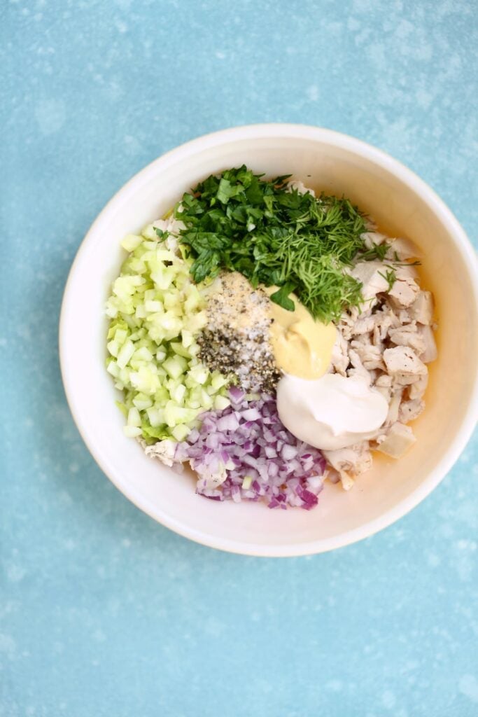 A bowl of ingredients for chicken salad, in a mixing bowl.