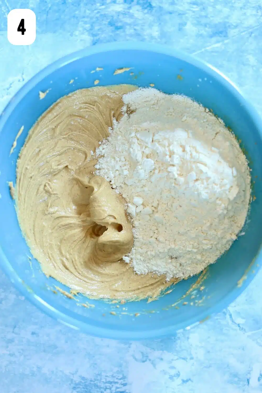 A blue bowl of ingredients for cupcakes with unmixed flour inside.