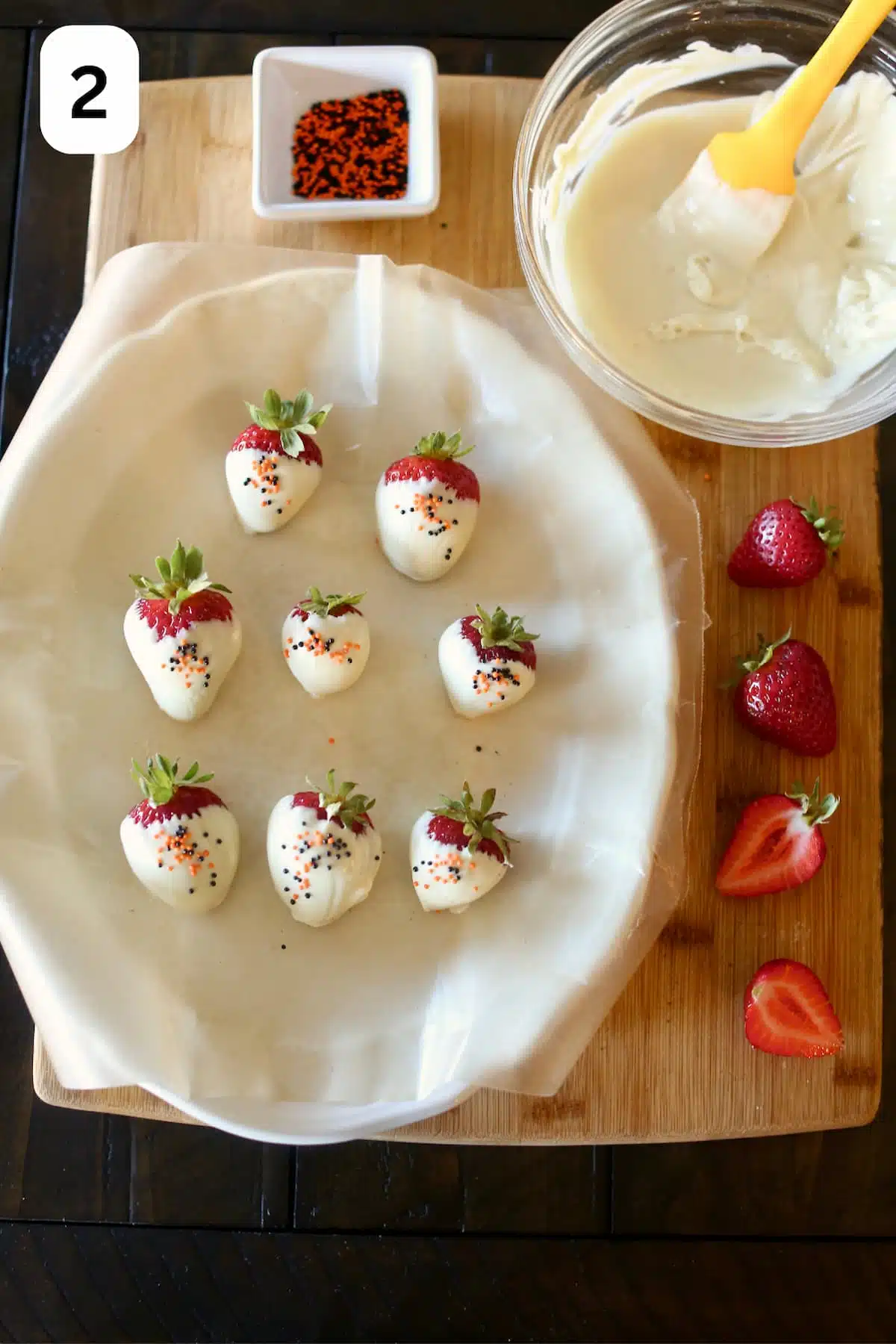 strawberries dipped in white chocolate are displayed on a platter.