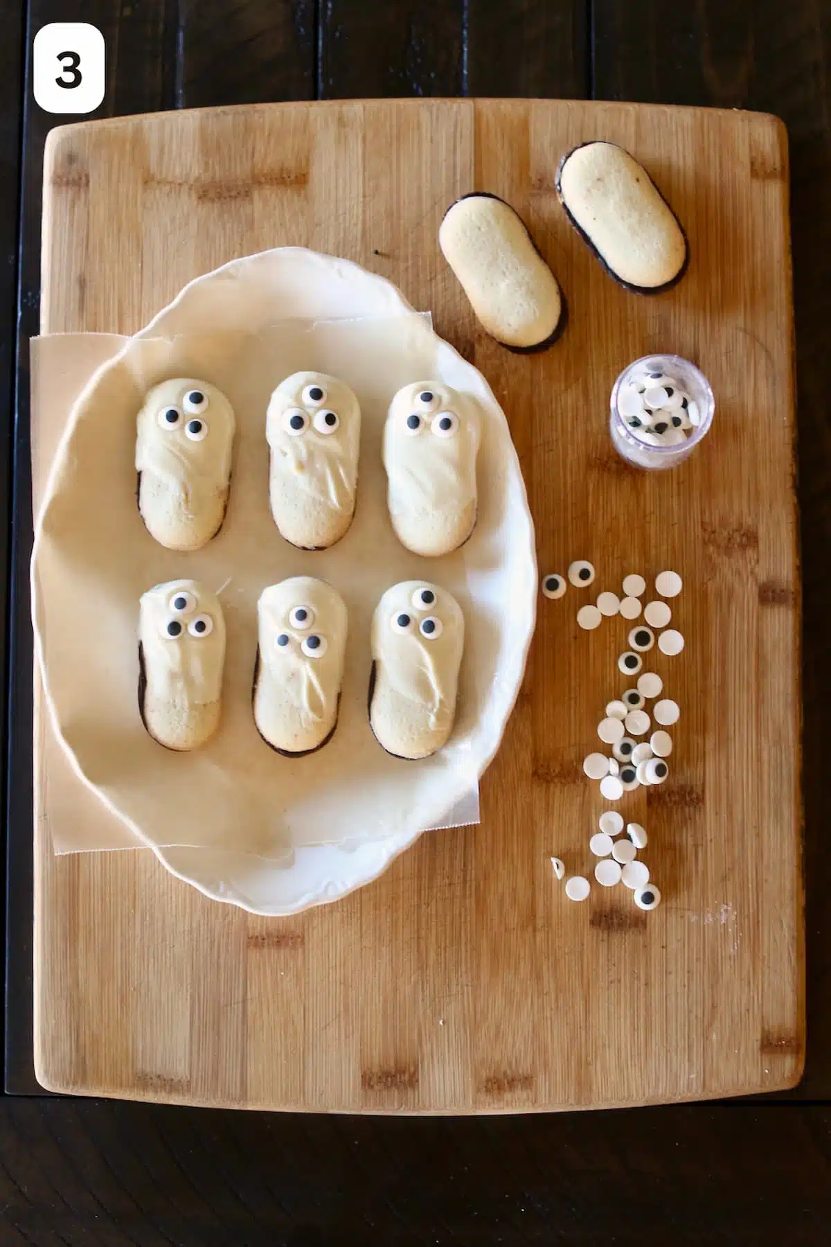Cookies have been dipped in white chocolate with candy eyes and displayed on a plate.