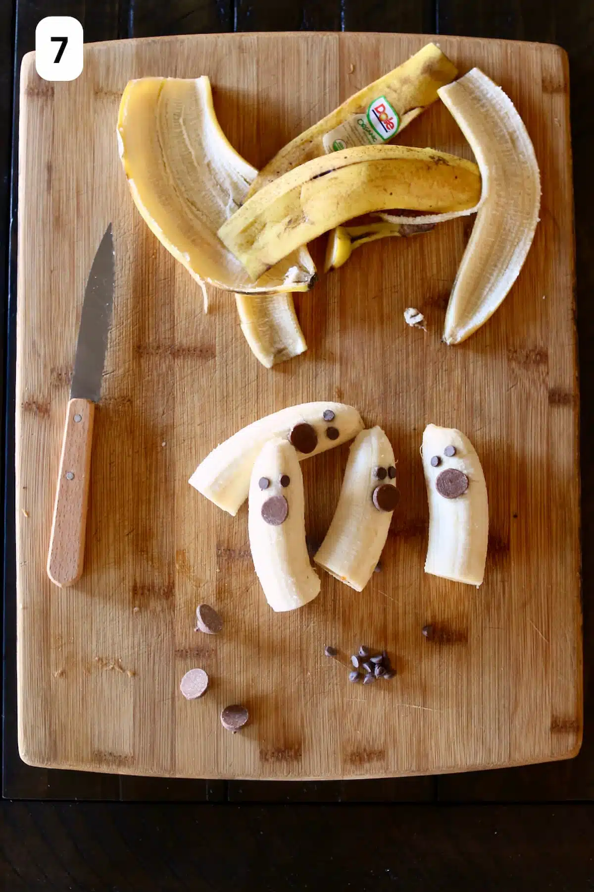 a cutting board with peeled bananas with decorations to look like ghosts.